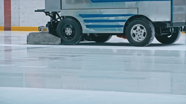 Zamboni resurfacing an indoor skating rink. Slow Motion. Ice resurfacer cleaning ice, machine cleaning and polishing smooth icerink. Ice harvester or restores ice.