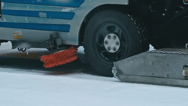 Zamboni resurfacing an indoor skating rink. Slow Motion. Ice resurfacer cleaning ice, machine cleaning and polishing smooth icerink. Ice harvester or restores ice.