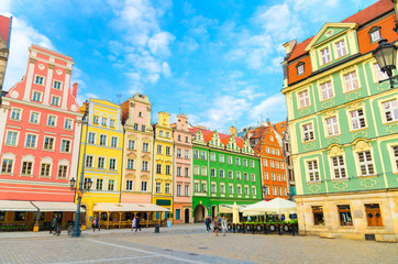 Row of colorful traditional buildings with multicolored facades and street lamp on cobblestone Rynek Market Square in old town historical city centre of Wroclaw, blue sky background, Poland - obrazy, fototapety, plakaty