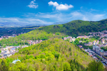 Fototapeta na wymiar Top aerial panoramic view of Karlovy Vary (Carlsbad) spa town with colorful beautiful buildings, Tepla river and hills of Slavkov Forest with green trees, West Bohemia, Czech Republic