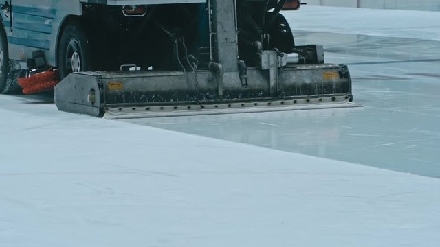 Zamboni resurfacing an indoor skating rink. Slow Motion. Ice resurfacer cleaning ice, machine cleaning and polishing smooth icerink. Ice harvester or restores ice.