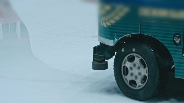 Zamboni resurfacing an indoor skating rink. Slow Motion. Ice resurfacer cleaning ice, machine cleaning and polishing smooth icerink. Ice harvester or restores ice.