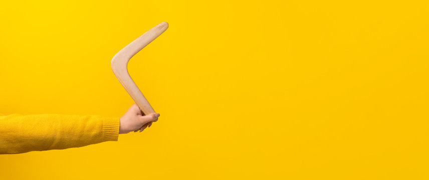 boomerang in female hand over yellow background, panoramic mock-up