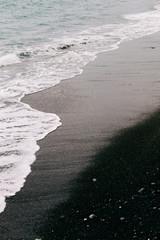 a sea wave arrives on the shore with black volcanic sand . beautiful natural background in Iceland