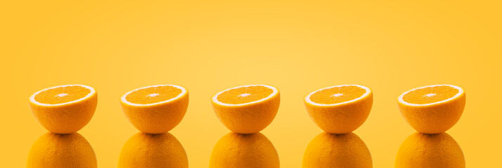 half sliced orange balancing on one whole orange on colorful background, panoramic image