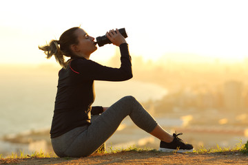 Runner resting hydrating drinking water at sunset
