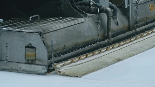 Zamboni resurfacing an indoor skating rink. Slow Motion. Ice resurfacer cleaning ice, machine cleaning and polishing smooth icerink. Ice harvester or restores ice.