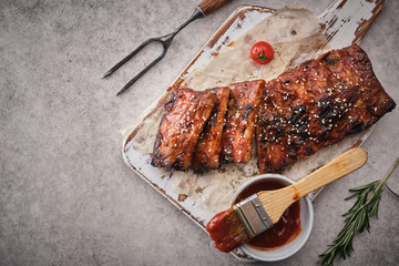 Delicious barbecued ribs seasoned with a spicy basting sauce and served on chopping board.