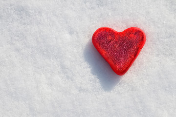 Fototapeta premium Red heart in sparkles on a white snow background.