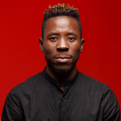 Obraz premium Portrait of an African man on a red background. Studio shooting
