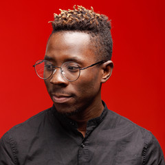 Fototapeta premium Portrait of an African man on a red background. Studio shooting