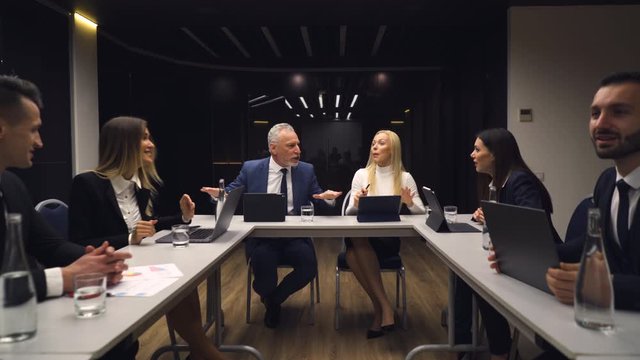 The business people sitting at the table and discuss emotionally