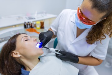 Patient sitting in dental chair, doctor dentist using professional medical equipment