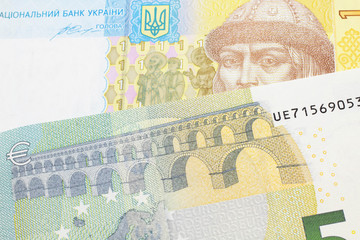 A close up image of a European five Euro note with a yellow and blue Ukrainian A Ukrainian one hryvnia bill close up in macro