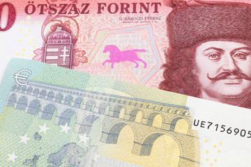 A close up image of a red, one hundred Hungarian forint bill close up with a blue and green five euro note from Germany in macro