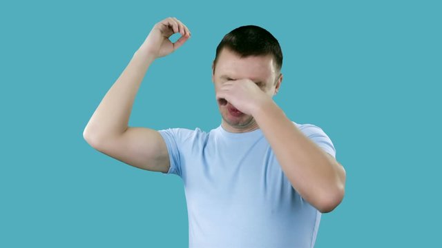 Man With Sweaty Armpit Covering His Nose With Hand. Bad smells concept.
