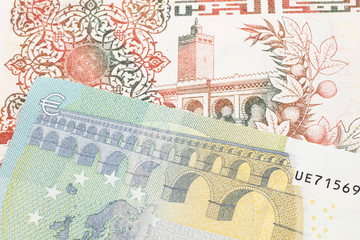 A beige, two hundred Algerian dinar bill with a red, European Union five euro bank note close up in macro