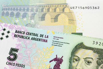 A five peso bill from Argentina, close up in macro with a red, five Euro European bank note