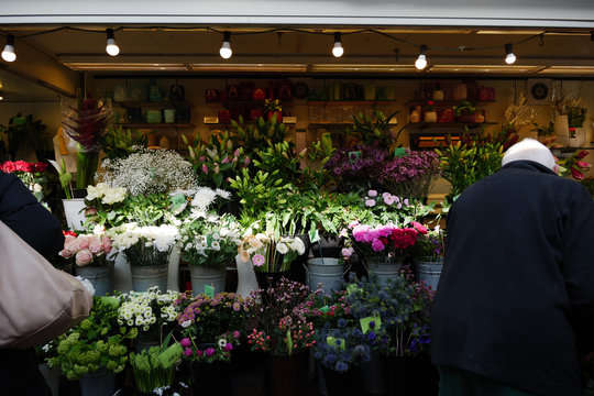 Customer choose colourful various bouquet of flowers in metal vases on shelf in front of flower stall or floral shop at farmer market at Carlsplatz, in Düsseldorf, Germany.   