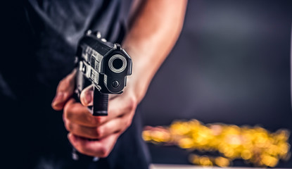Killer with gun close-up pointing a gun at the target. Robbers used the gun to robbery the money.