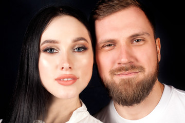 Two faces side by side, a guy and a girl, close-up portraits on a black background. Concept love, couple in love, relationship.