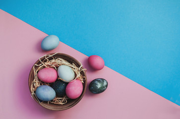 Easter greeting background with dyed multicolored chicken quail eggs on straw in plate