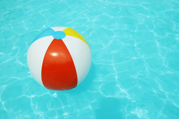 Obraz premium An inflatable beach ball floats in a pool on a summer day
