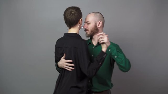 Romantic couple dancing on gray background. Man and woman are dancing slow blues dance. Sensual couple dancing.