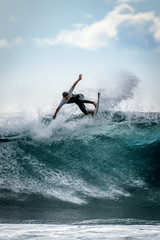 Young surfer with with wetsuit enjoying big waves in Tenerife, Canary Islands. Sporty boy riding...