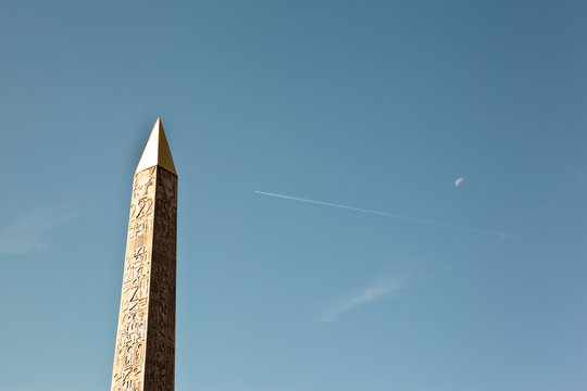 Egyptian obelisk with moon and plane background