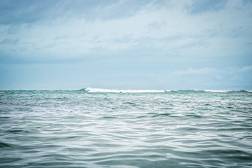 Fototapeta na wymiar Sea wave horizon turquoise water blue dramatic overcast sky landscape surfing lifestyle