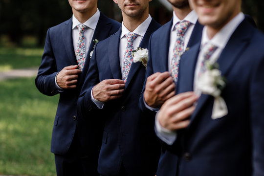 elegant groom's men with sttlish flowers tie. white Flowers in buttonhole, the groom's men are dressed in a dark suit. Wedding day. Outfit of the day.