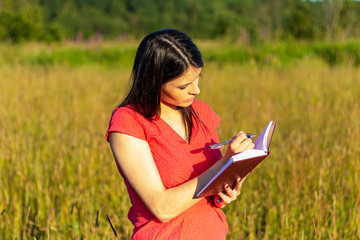 Naklejka na ściany i meble Caucasian girl with a notebook on nature