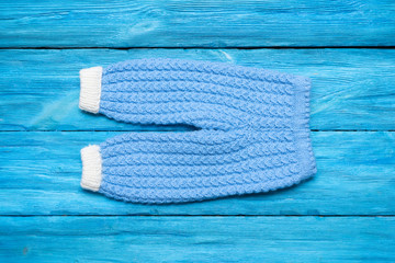 Children warm knitted clothes on blue wooden table background.