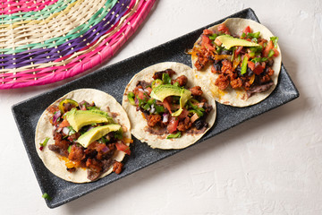 Mexican pork chorizo tacos with avocado and beans on white background