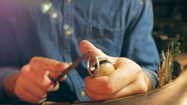 Working jeweller grinds a silver ring.