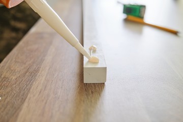 Carpenter male using construction glue when working with wooden board