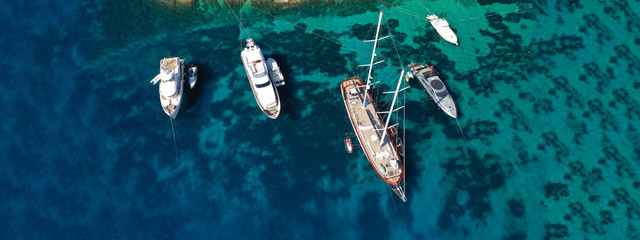 Aerial drone ultra wide photo of yachts docked in famous beach of Super Paradise with turquoise...