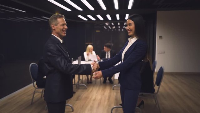 The businessman and businesswoman handshaking in the meeting room. slow motion