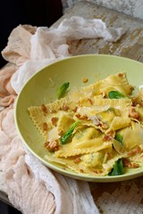 Italian food. Home made fresh Ravioli pasta with spinach and ricotta cheese, fresh basil and, black pepper, parmesan cheese and Butter Sauce on a light aged background.