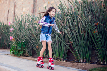 Smiling kid girl roller skate in the park. Children and activity concept