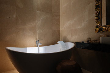 Stone bath tub in luxury interior hotel with sun light from top. Organic spa relaxation in Bali bathroom.