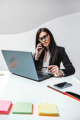 young business woman with laptop talking on the phone in office
