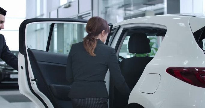 Serious Caucasian driver opening car door for busy brunette businesswoman. Professional male chauffeur working for rich successful woman. Cinema 4k ProRes HQ.
