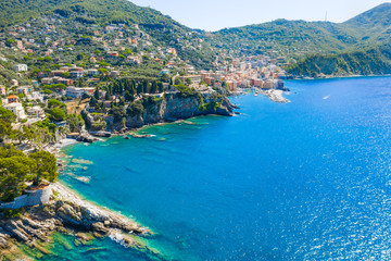Obraz premium Aerial view on the city with colorful houses located on the rocky coast of ligurian sea, Camogli near Genoa, Italy. Rocky Coastline is washed by turquoise blue water.