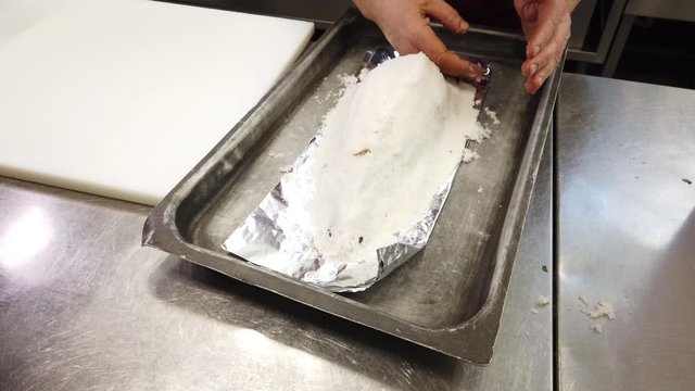 Chef preparing dorade fish in salt crust