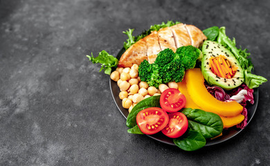 Bowl Buddha. chicken, broccoli, chickpeas, pumpkin, avocado, carrot, tomato on   a stone background  with copy space for your text