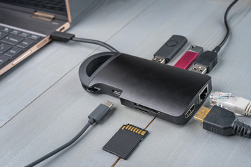 USB Type C adapter or hub connected to the laptop with various accessories - pendrives, hdmi, ethernet, memory card, cables. - obrazy, fototapety, plakaty