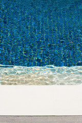 Swimming pool with blue tiles and wavy water. Abstract full frame image.