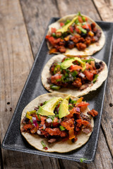 Mexican pork chorizo tacos with avocado and beans on wooden background